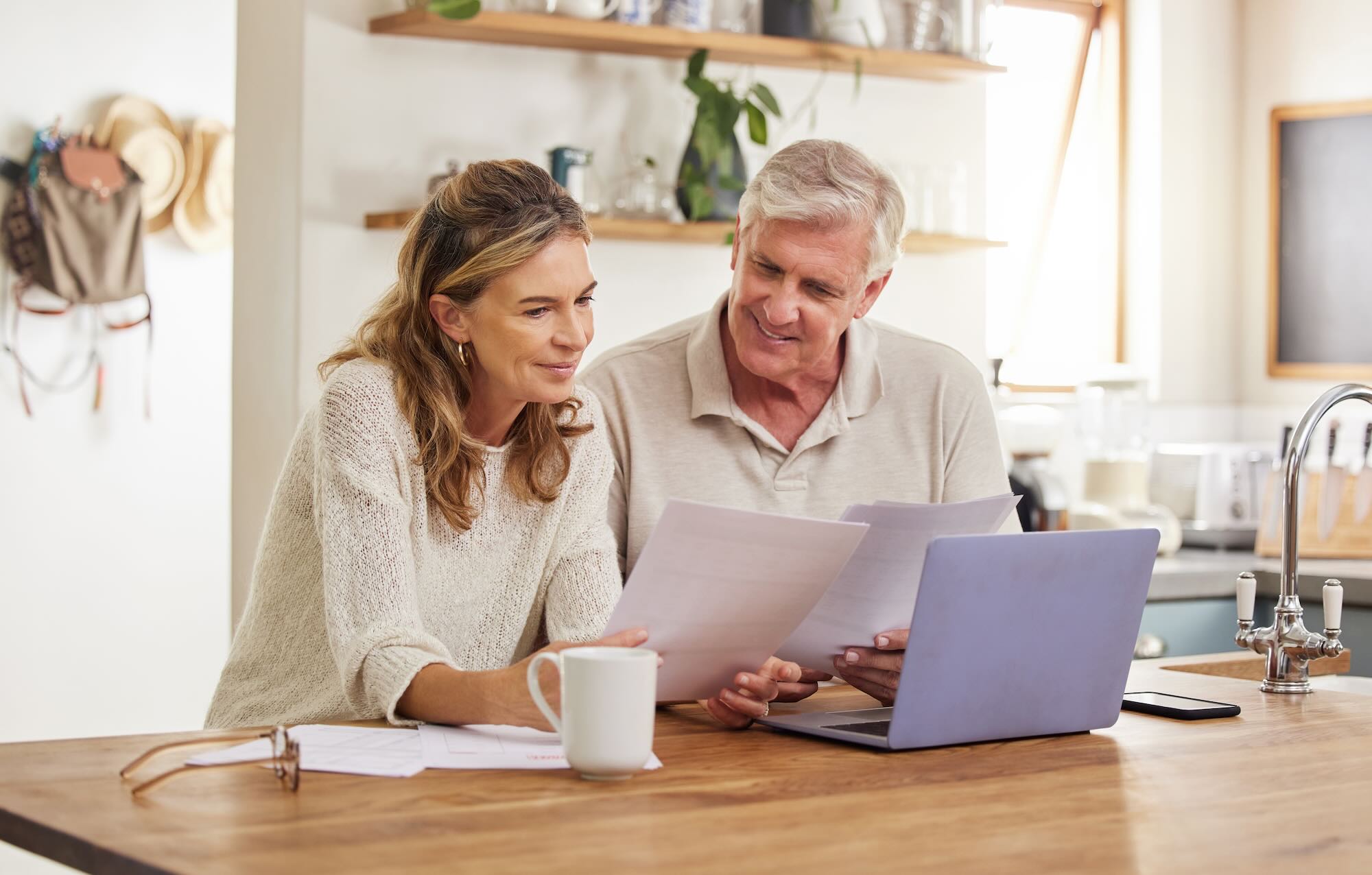 Senior couple looking through documents sitting at their kitchen 